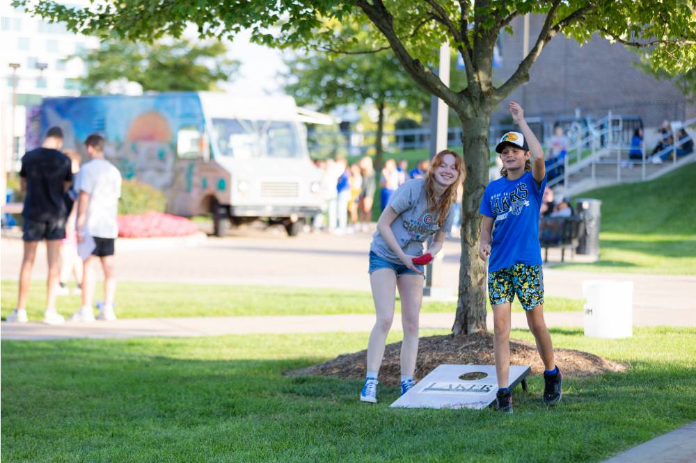 People playing cornhole on Kirkhof Lawn with food truck in the background.